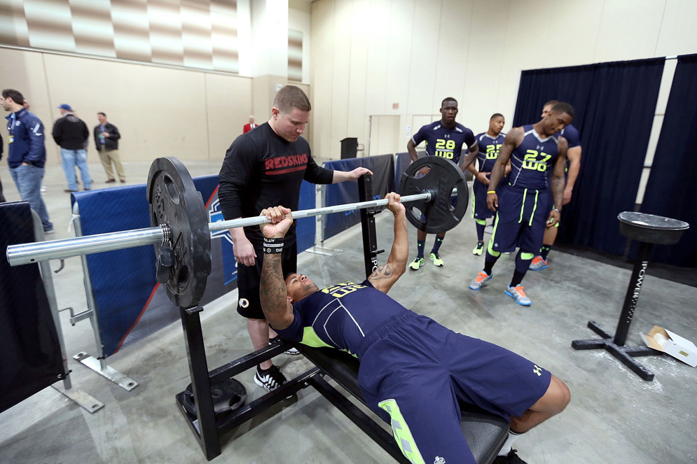 Scouts watch as an NFL prospect completes the bench press. (AP)