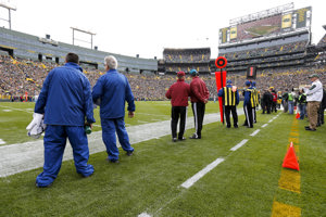 Game day employees stand on the side of the field on game day.